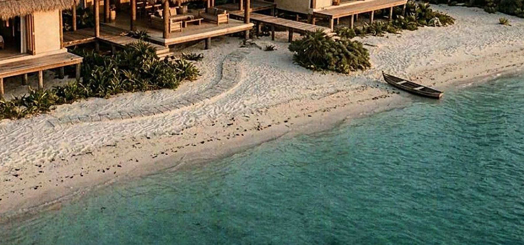 Orilla y agua turquesa vistas desde el aire, con una canoa de madera